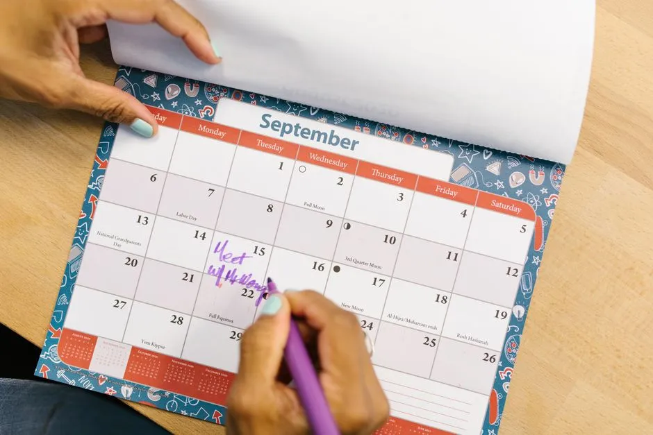 Marking dates on a printed wall calendar with a marker